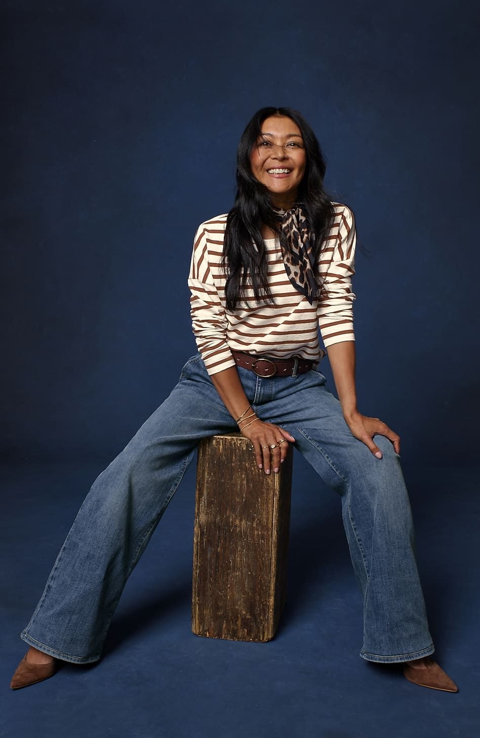 Woman over 50 wearing medium wash wide leg jeans with a fitted striped tee tucked in, a balanced denim outfit with pointed toe flats.