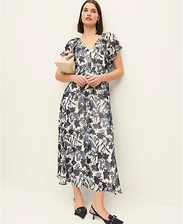 Ivory midi dress with a navy floral print and flutter sleeves, worn with a small clutch.