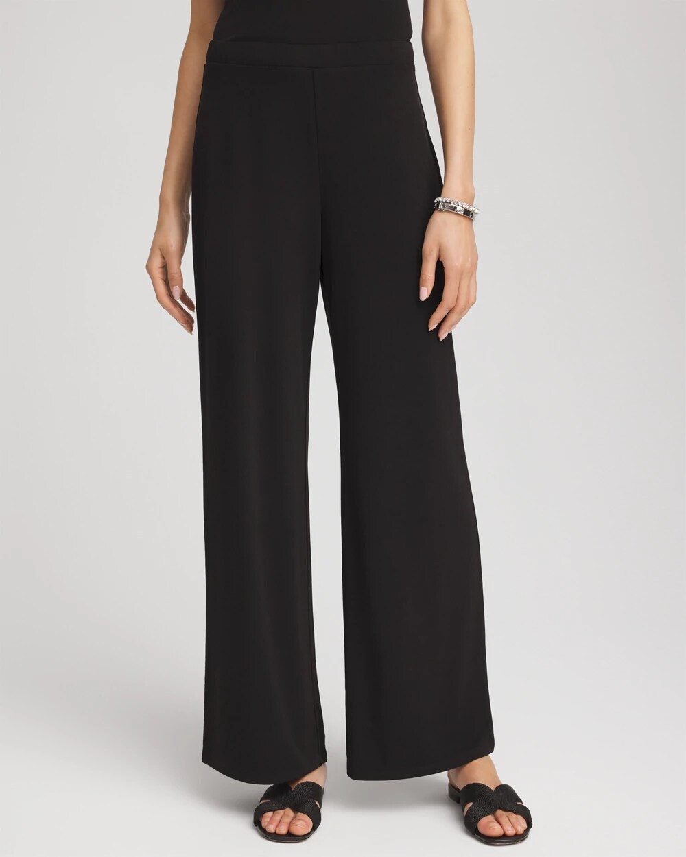 Woman over 50 wearing knit wide leg pants with a silky top and low mules, an easy evening outfit.