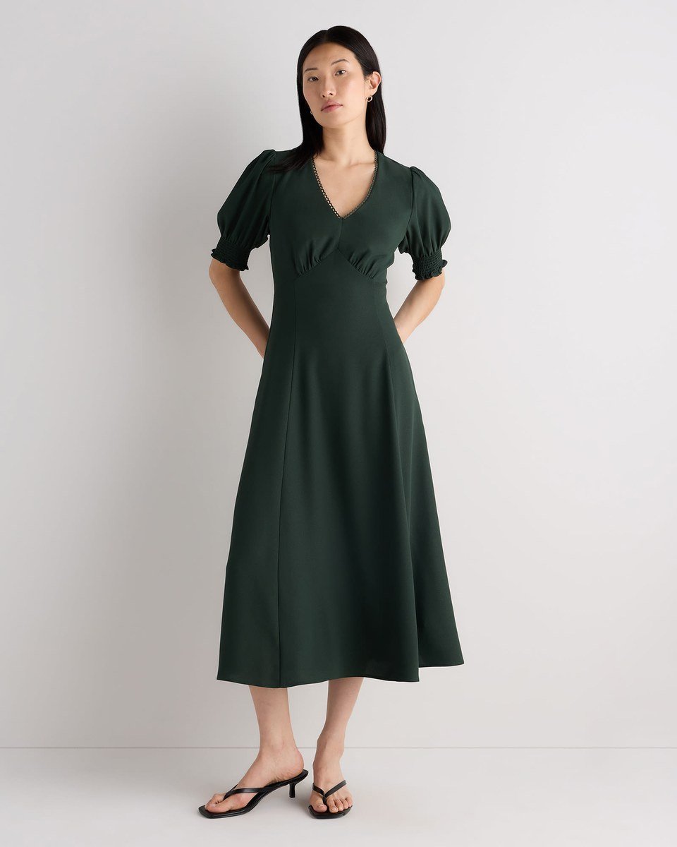 Forest green crepe midi dress with puff sleeves and a lattice trim V neck, worn by a woman over 50.