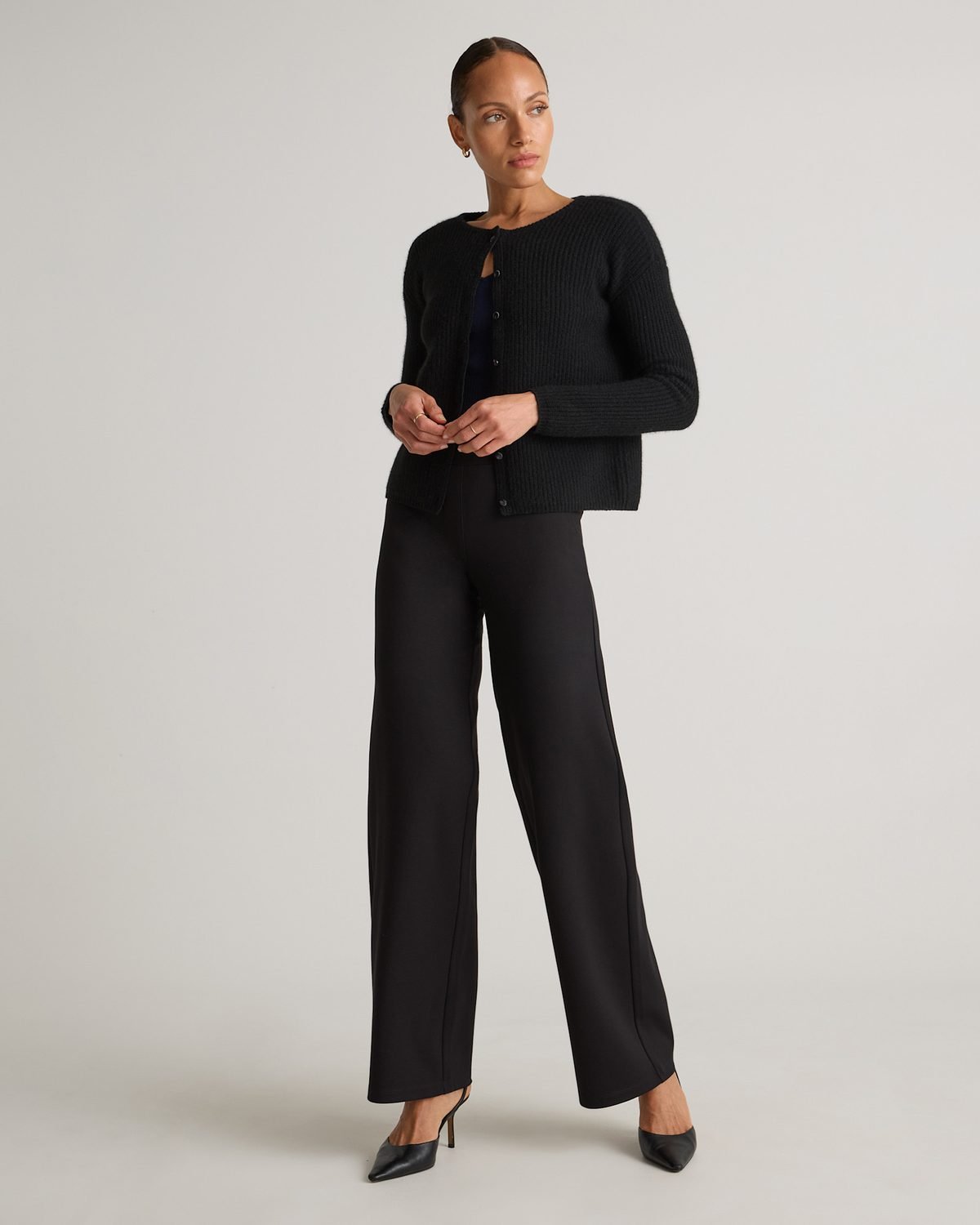 Woman over 50 wearing black ponte wide leg pants with a white button down shirt half tucked, a polished everyday outfit.