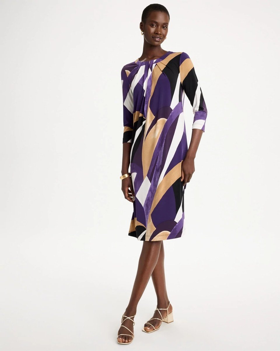 Purple abstract print knit dress with three quarter sleeves and a twist front, worn by a woman over 50.