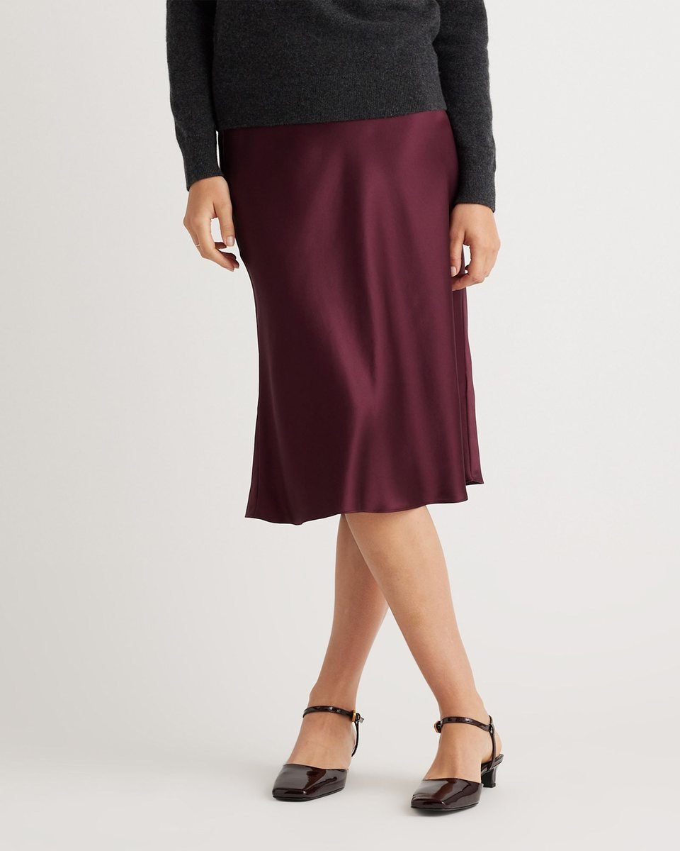 Wine red silk satin midi skirt with a bias cut, worn with a charcoal sweater and low heeled Mary Jane shoes.