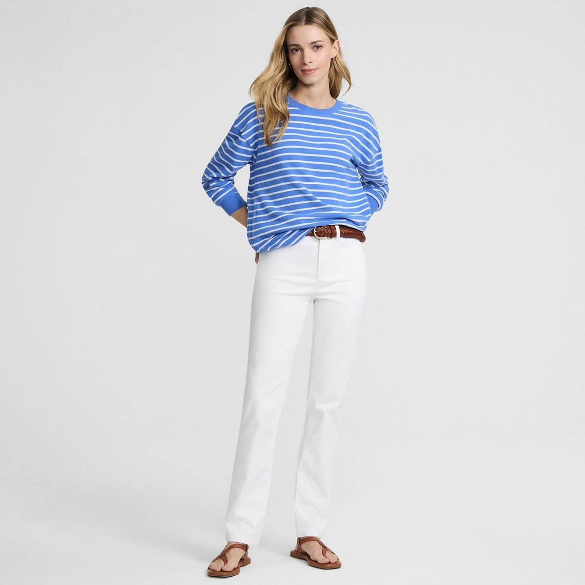 Woman over 50 wearing white high rise straight leg jeans styled for fall with a dark knit top.