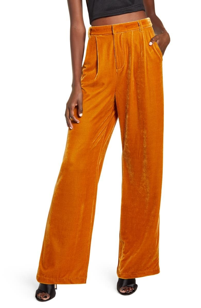 Woman over 50 wearing velvet wide leg pants with a fitted black knit top and low block heels, a dressy evening outfit.