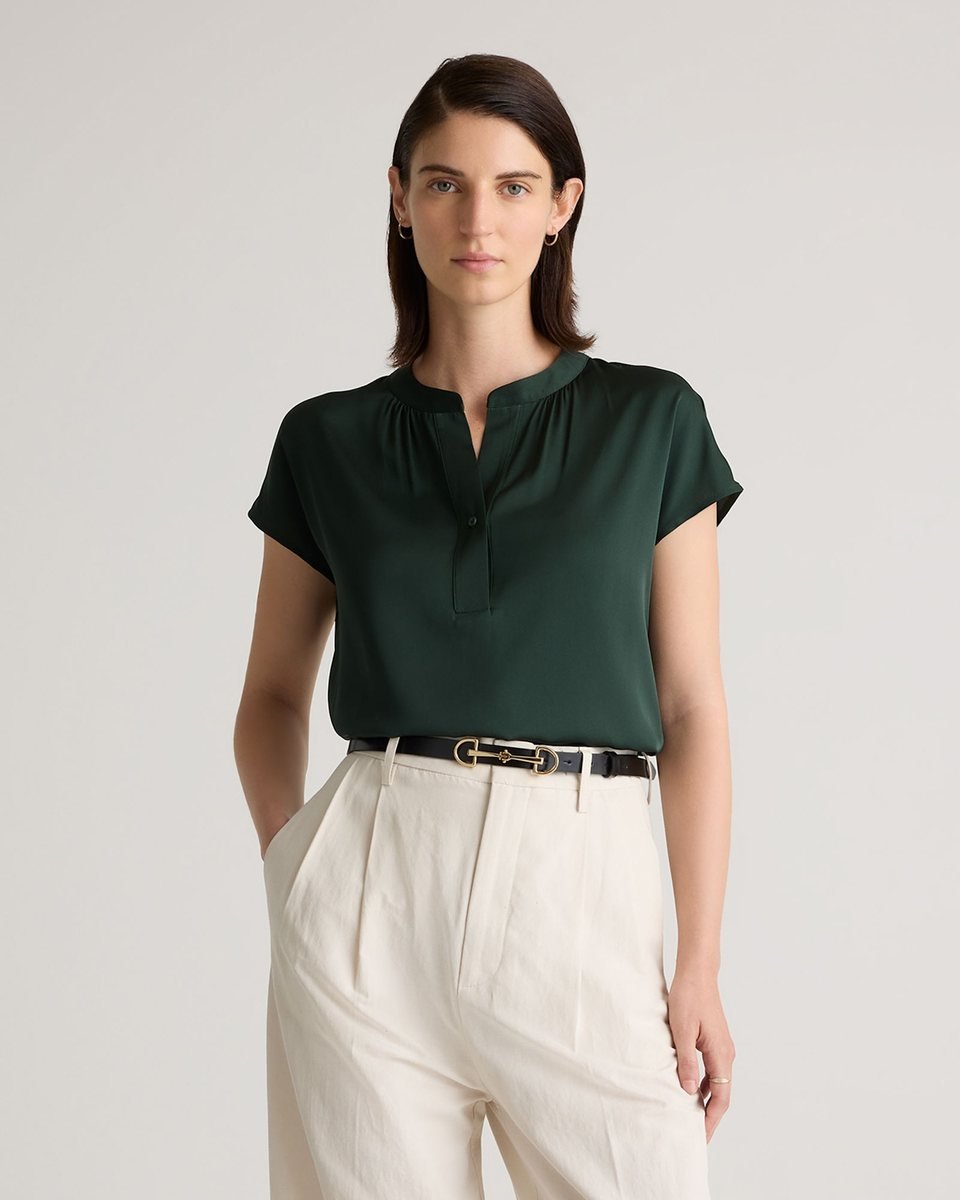 Forest green washable silk dolman sleeve blouse with a band collar, worn tucked into cream trousers.