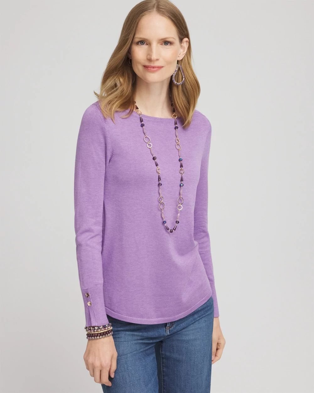 Woman over 50 wearing a soft berry pullover sweater with a bateau neckline and dark jeans.