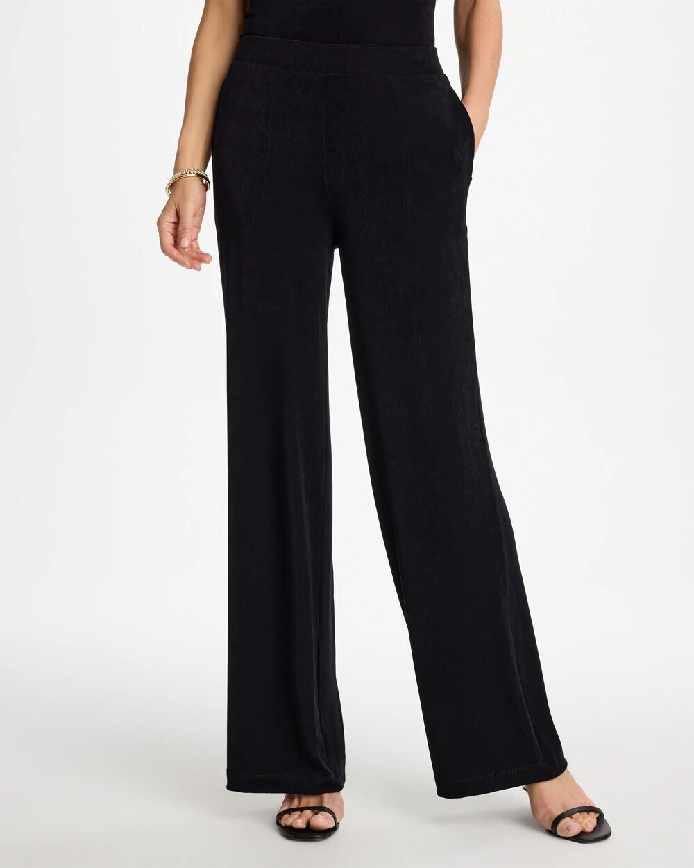 Woman over 50 wearing wide leg pull on pants with a jewel tone sweater, front corner tucked, a polished travel outfit.