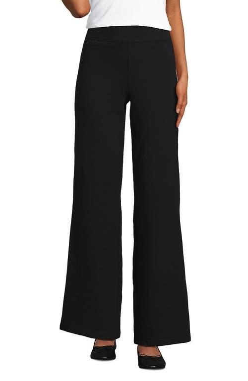 Woman over 50 wearing black high rise wide leg pants with a black top in a one color column outfit.