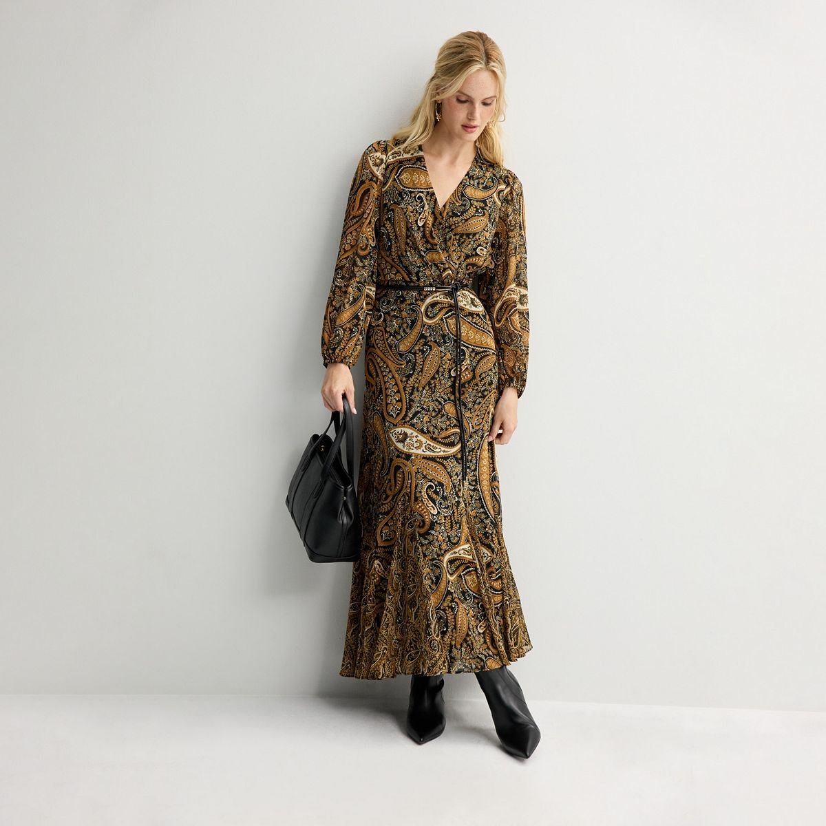 Antique gold paisley surplice maxi dress with long sleeves and a slim belt, worn with black boots.