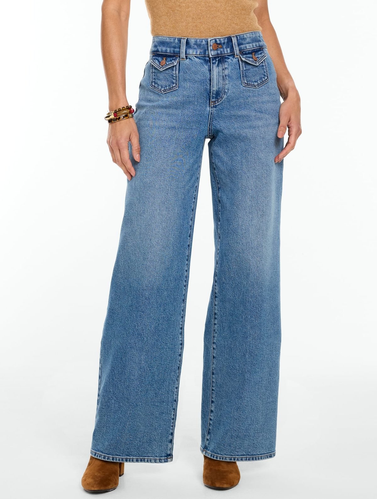 Woman over 50 wearing light wash wide leg jeans with a fitted navy sweater tucked in, a casual polished outfit.