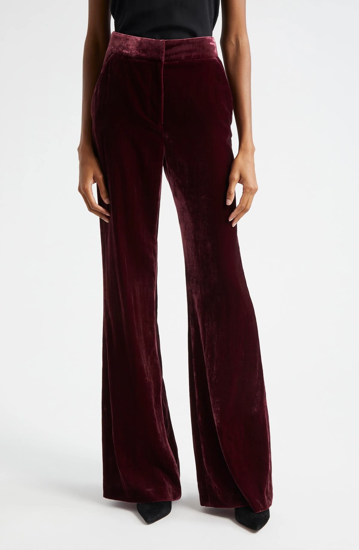 Woman over 50 wearing velvet wide leg pants with a high rise and a fitted black knit top, a dressy Thanksgiving guest outfit.