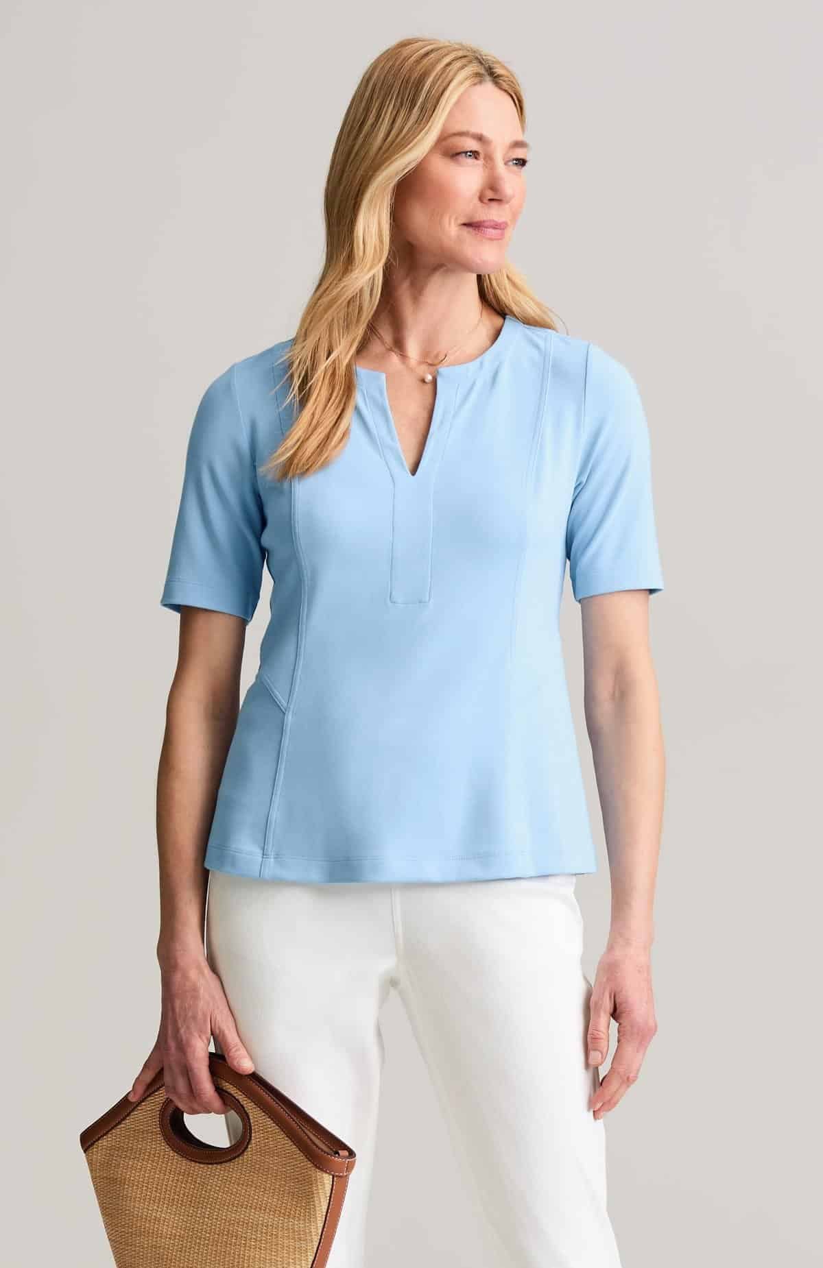 Seamed elbow sleeve knit top with a hem below the belly, worn with slim pants by a woman over 50.