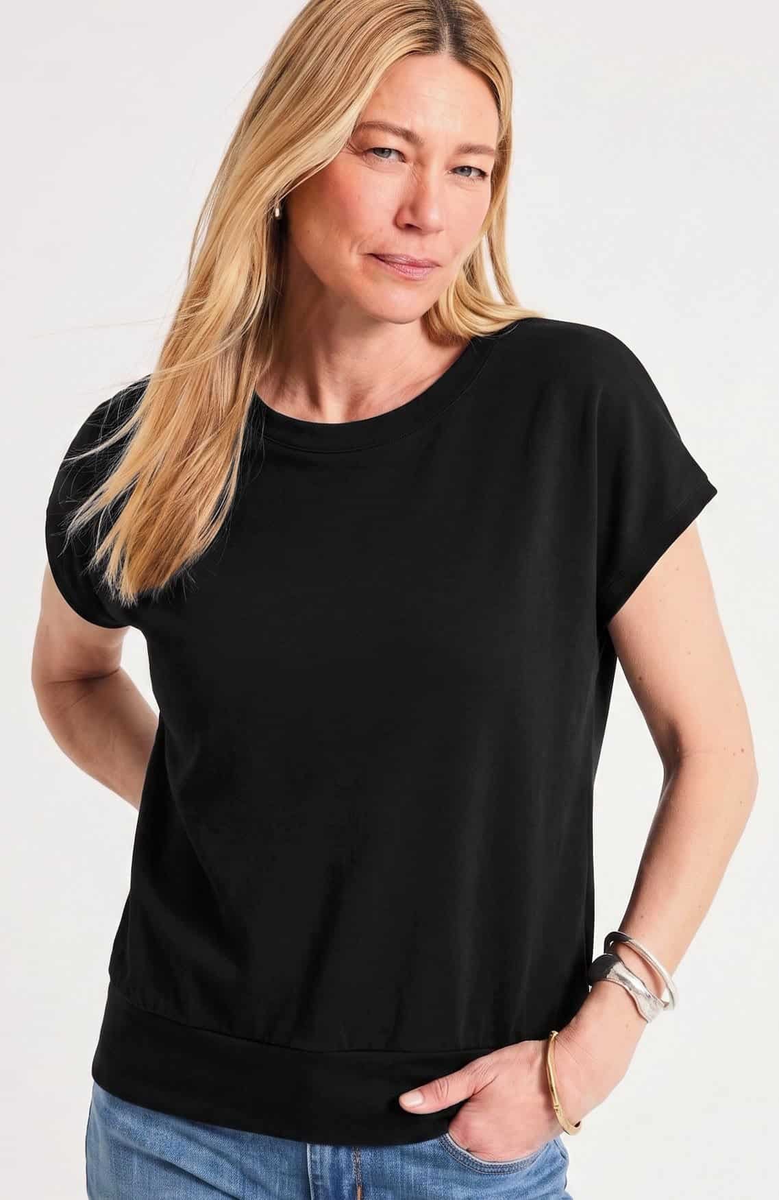 Banded hem top with soft blousing over the tummy, worn with slim pants by a woman over 50.