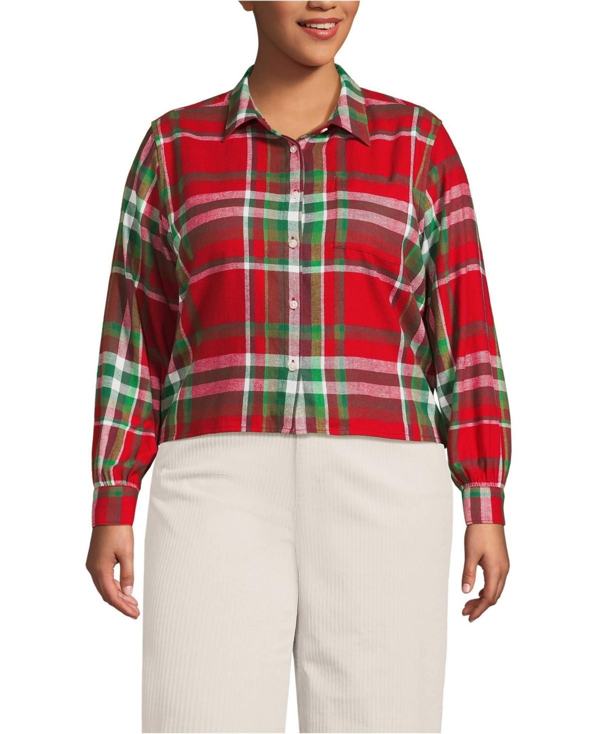 Woman over 50 wearing a red and green plaid flannel shirt open over a white tee with optic white jeans.