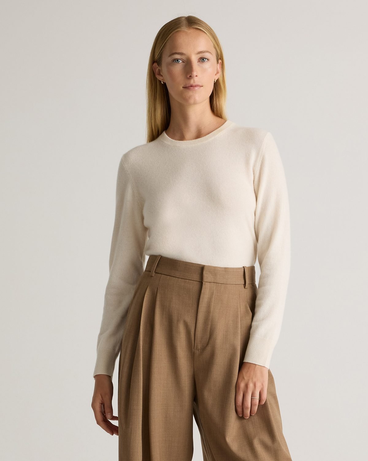 Woman over 50 wearing an ivory cashmere sweater with alabaster ankle jeans and brown booties.