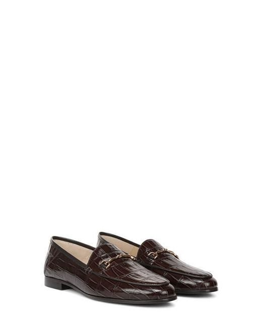 Woman over 50 wearing alabaster ankle jeans with a brown cashmere sweater and brown croc embossed leather bit loafers.