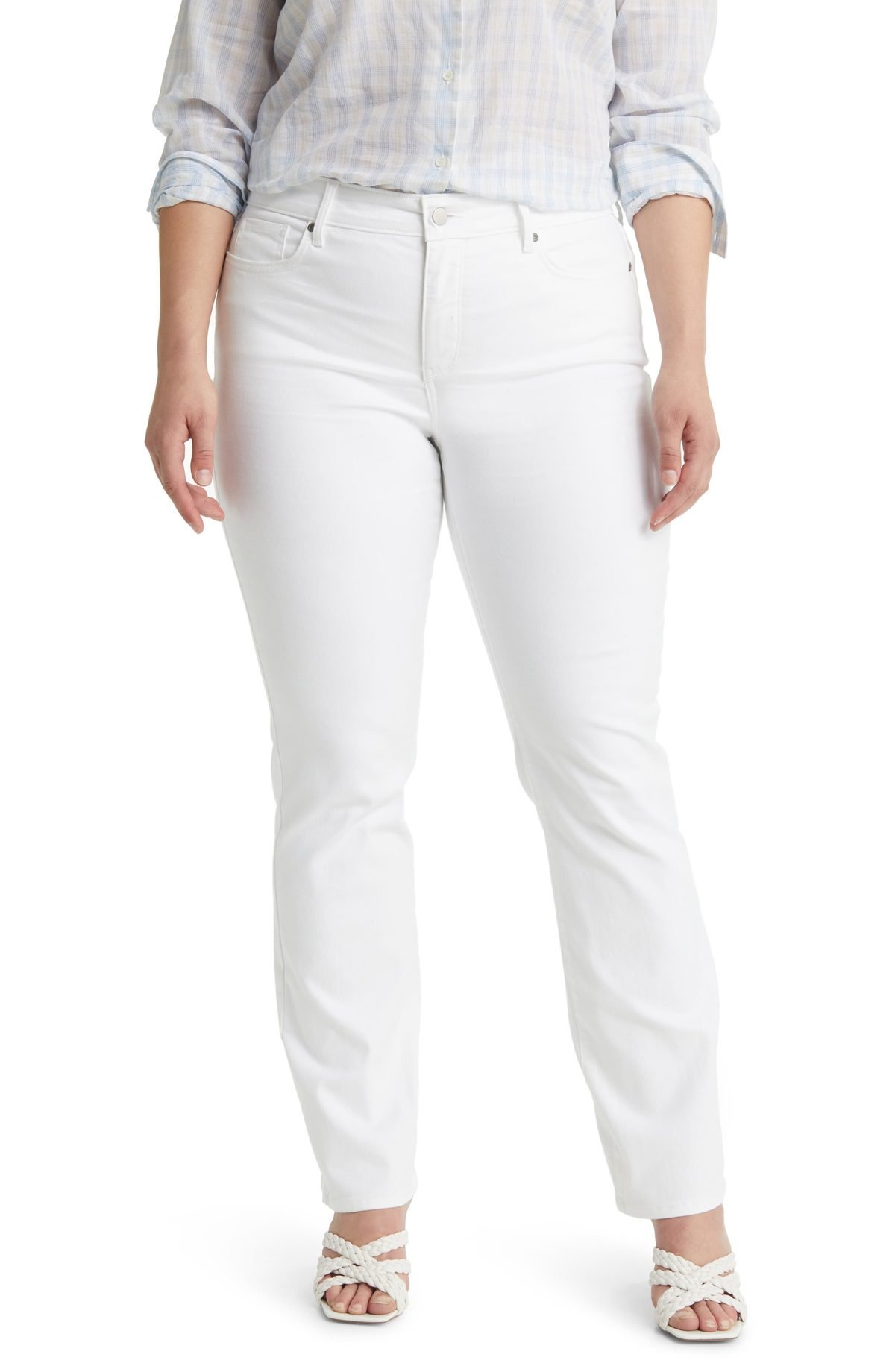 Woman over 50 wearing optic white straight leg jeans with a camel cashmere crewneck and brown loafers.